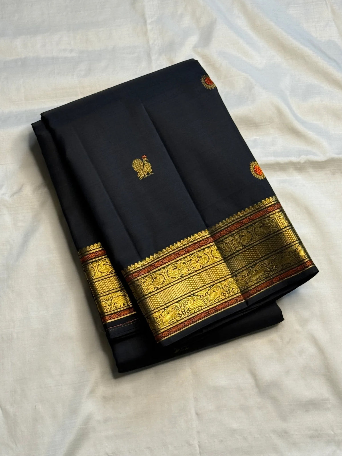 Black Kanchipuram silk body with gold and rust-accented meenakari buttas.