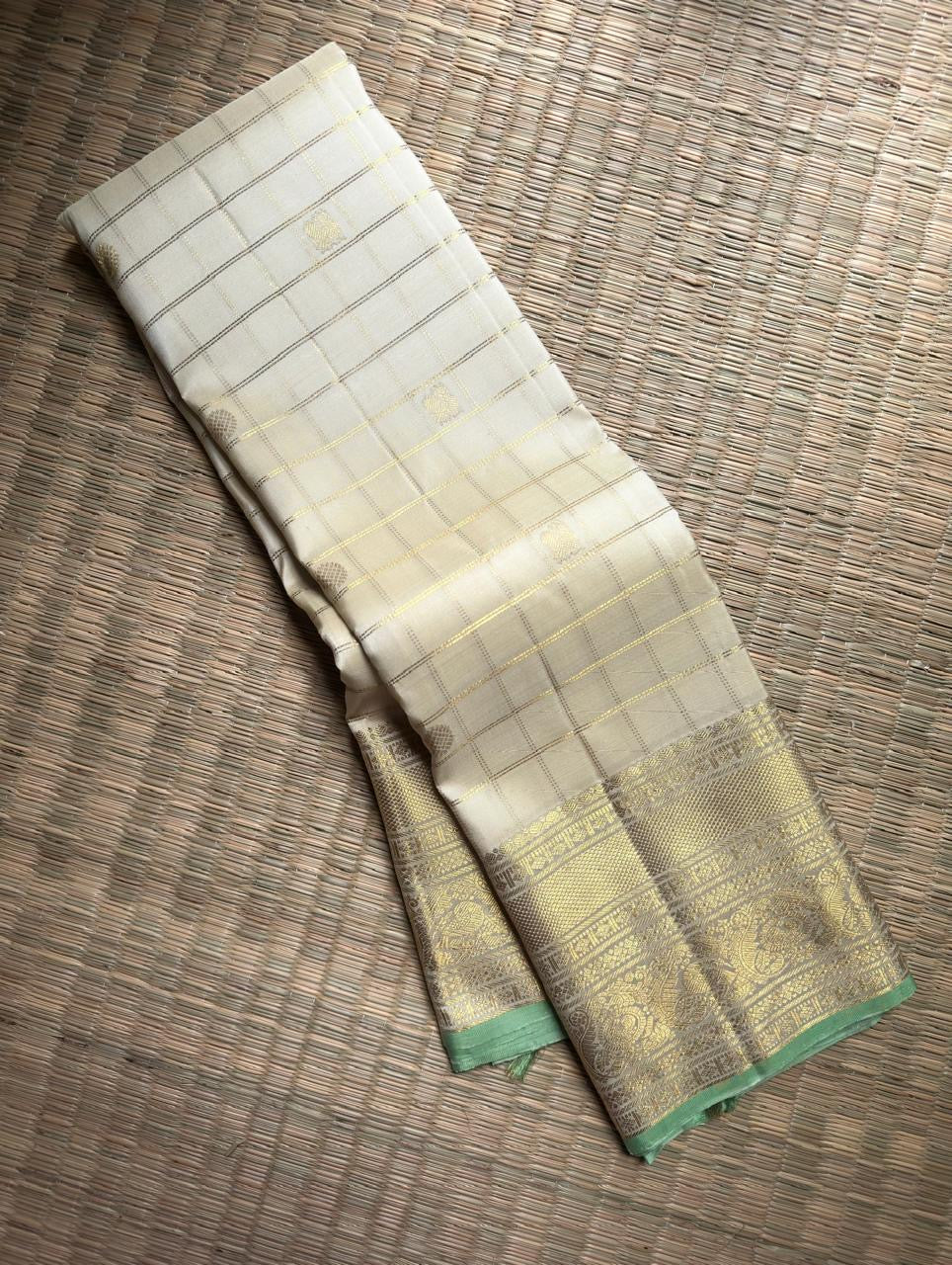 Warm Ivory Zari Kattam saree opened to show Kamalam buttas and elaborate Peacock and Benares Pettu border.