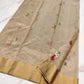 Champagne beige Chanderi saree laid open showing pink, ivory and green floral buttas and the gold border