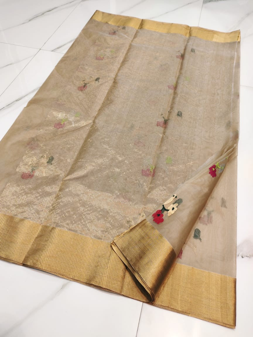 Champagne beige Chanderi saree laid open showing pink, ivory and green floral buttas and the gold border