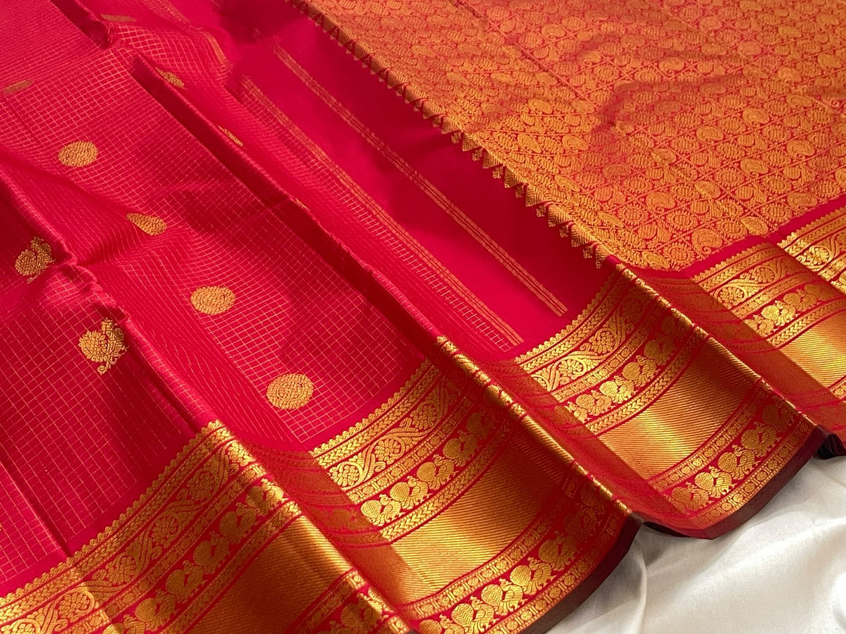 Kumkum red Kanchipuram silk saree showing fine gold zari kattam checks and Mayil Chakram buttas