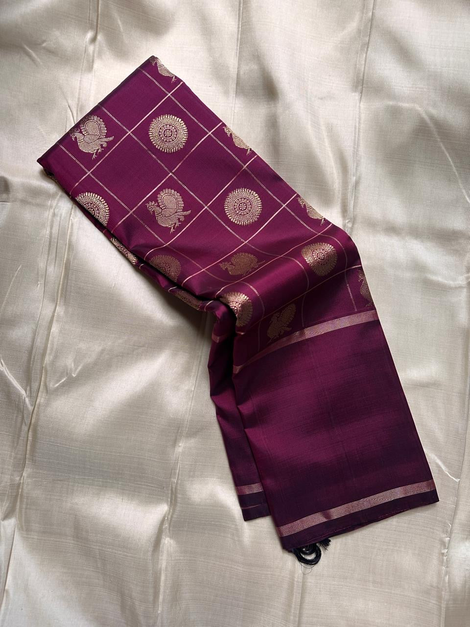 Partially draped plum Pure Kanchipuram silk saree with zari checked body, scattered woven motifs, and slim zari border.
