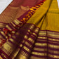 Handwoven mustard-yellow Kanchipuram silk body contrasted with a richly ornamented red-maroon border.