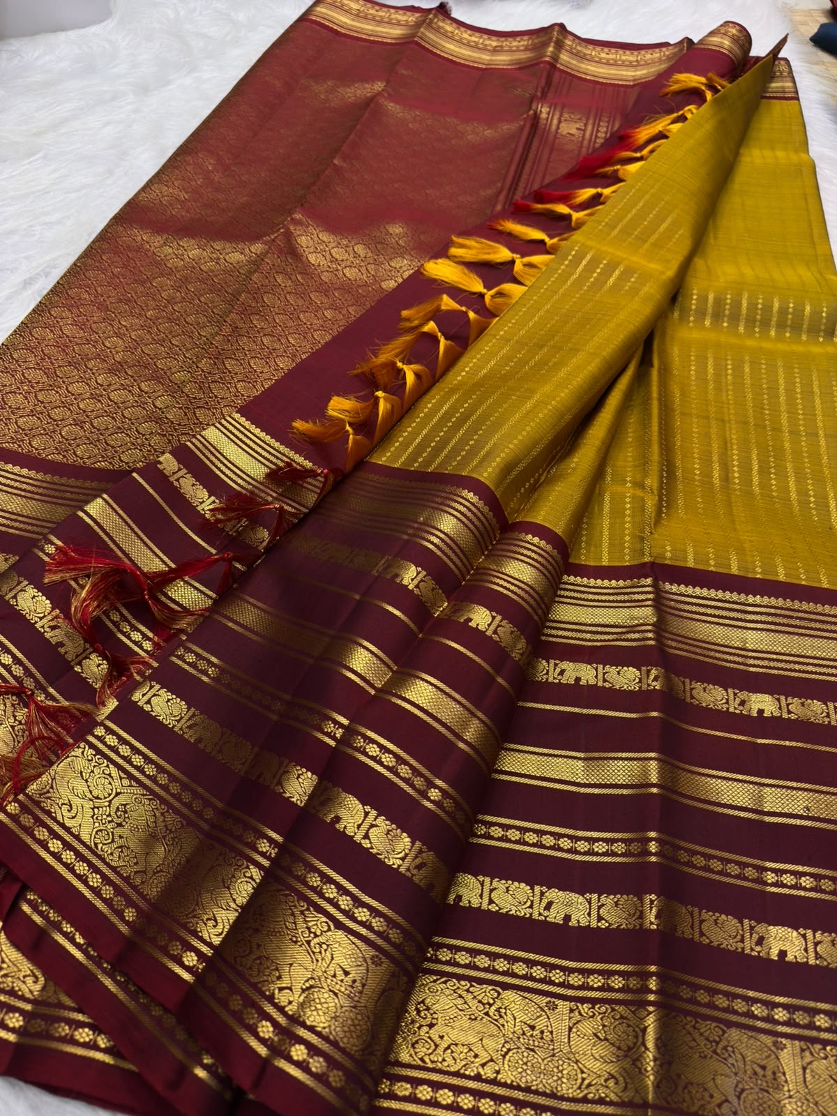 Handwoven mustard-yellow Kanchipuram silk body contrasted with a richly ornamented red-maroon border.