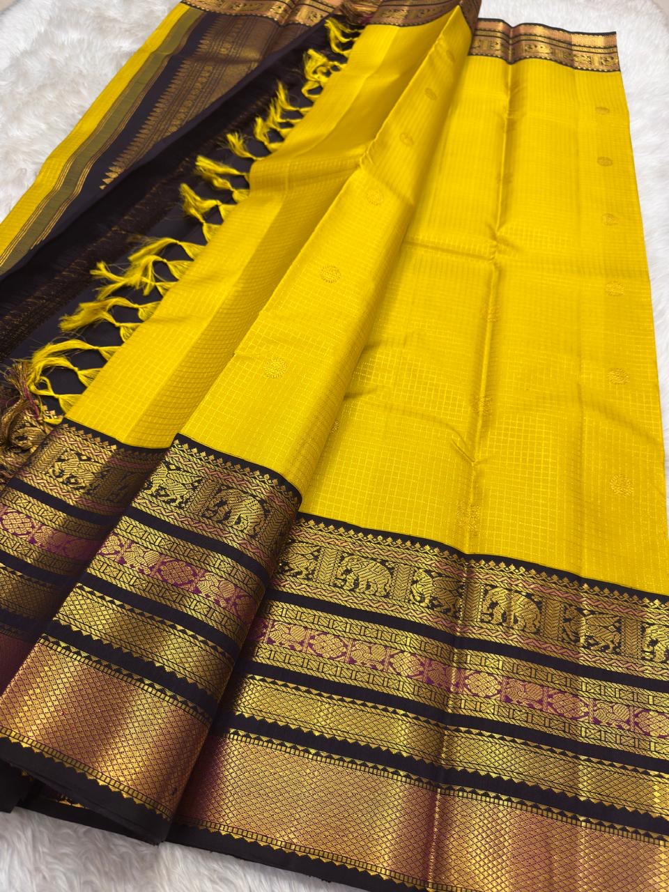 Mustard yellow Kanjipuram saree folded to show Zari Kattam body and contrast black border