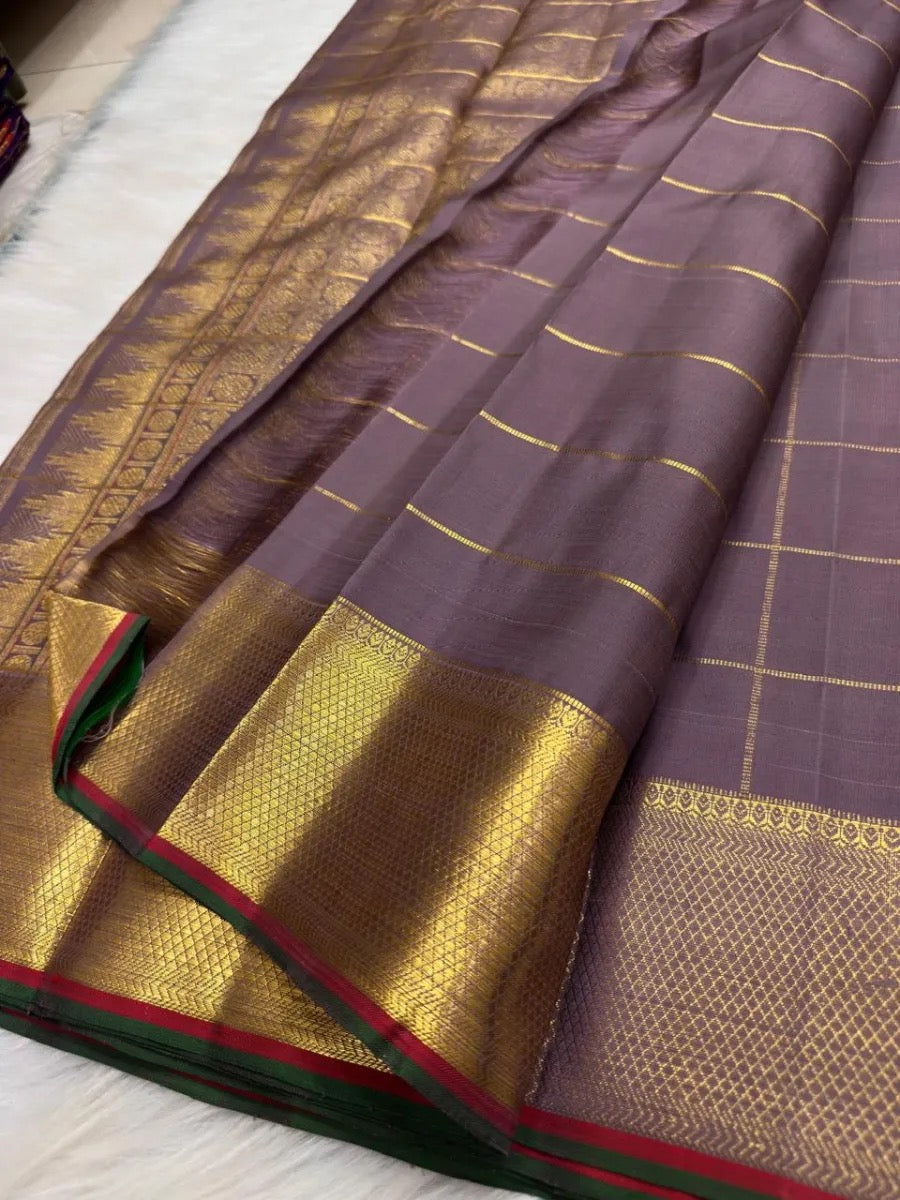 Muted purple-brown pure silk Kanchipuram saree with traditional zari motifs and gold lattice body.
