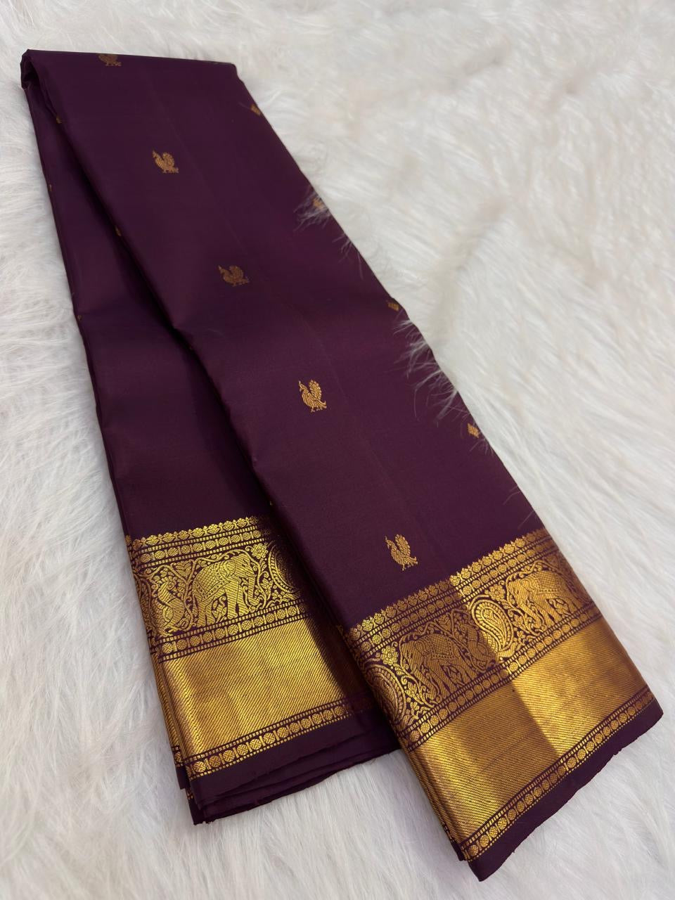 Naval Pazham plum pure silk Kanchipuram Butta saree, spread in pleats, with antique-gold border