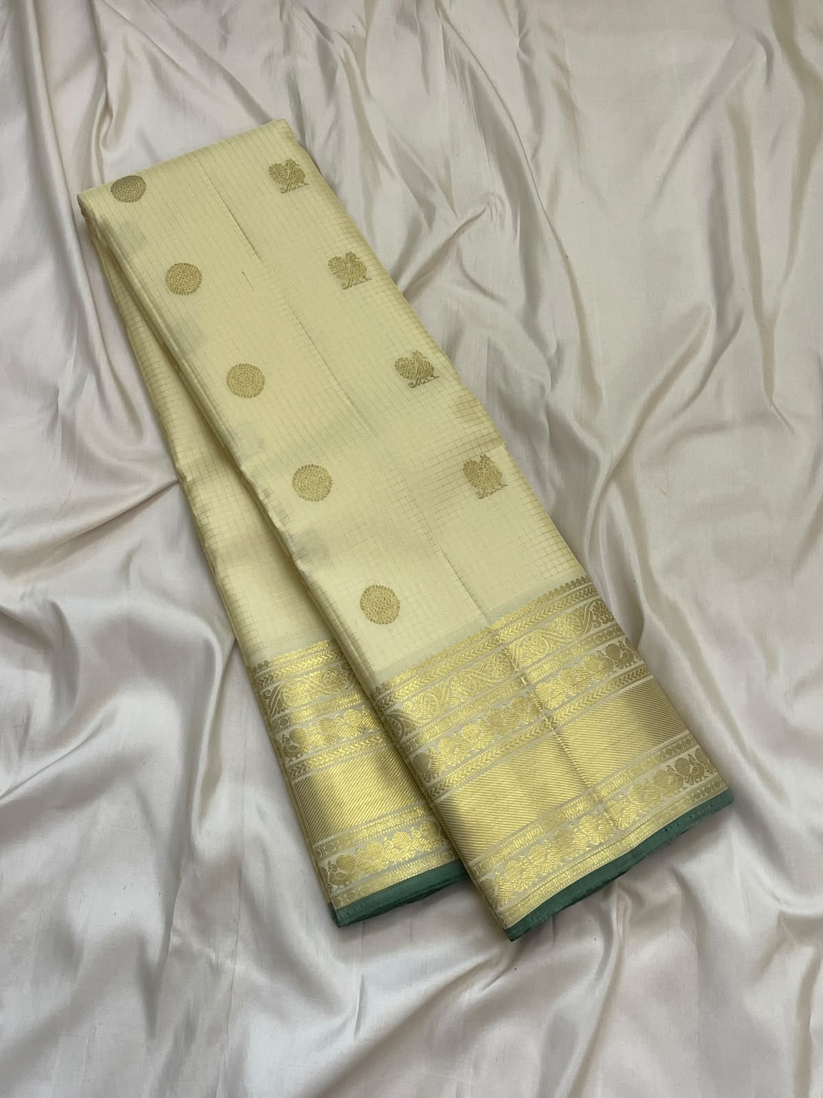 Handwoven warm ivory Zari Kattam Kanjipuram saree with dark green selvedge and gold zari detailing