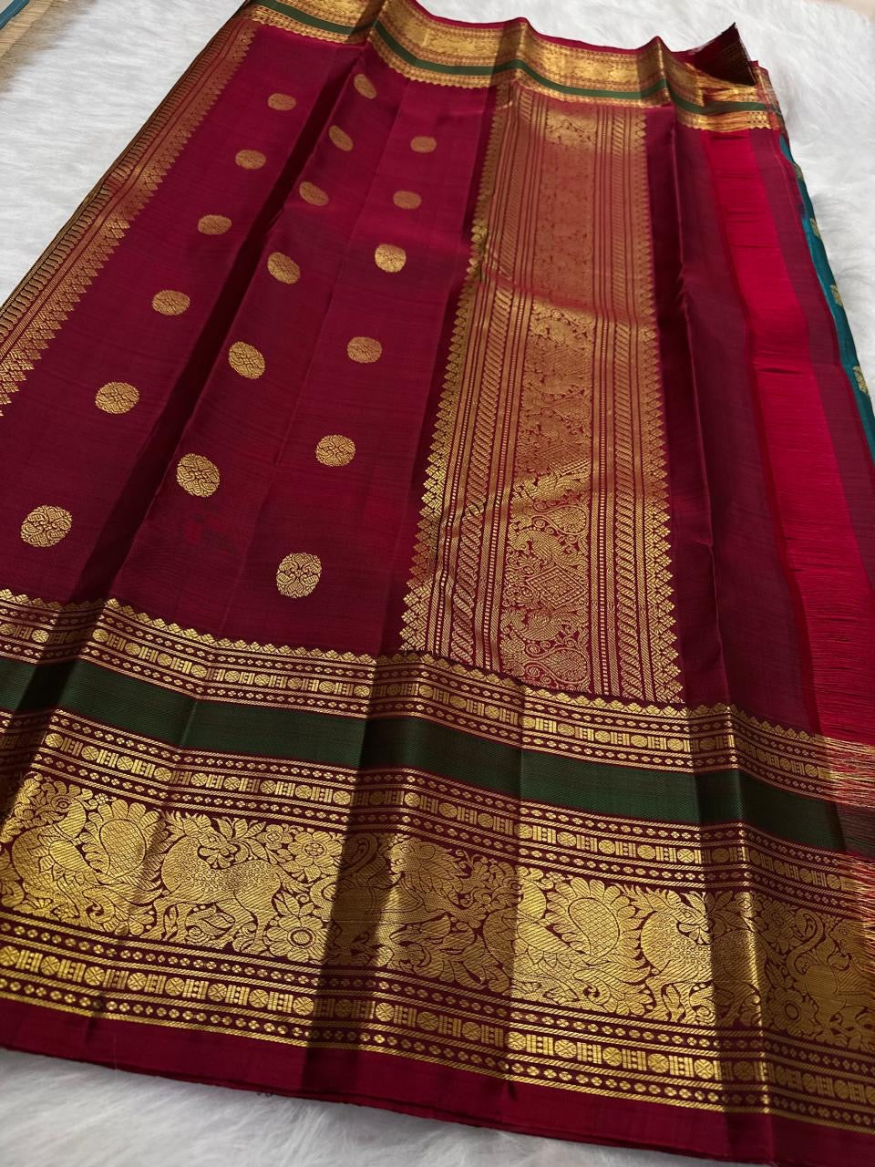 Folded navy blue Kancheepuram pure silk saree showing Yaanai Ambari Butta body and deep red Vanasringaram border