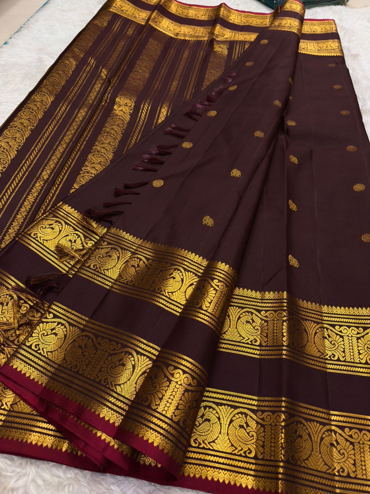 Ornate self-colour border of deep wine plum Kanjipuram saree with dense Maanga and Yaanai antique gold zari array