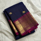 Folded navy Pure Kanchipuram silk saree with gold elephant buttas and a wide magenta-and-gold zari border on white fabric.