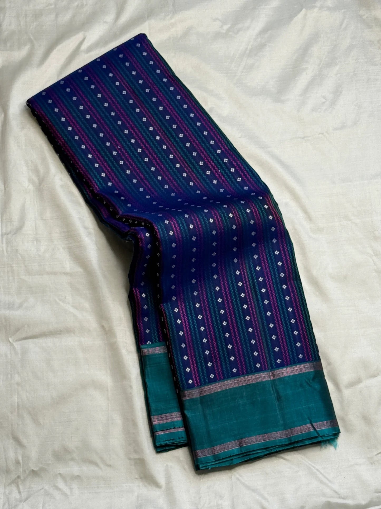 Full navy Kanchi Pattu saree with jewel-tone butta work, folded view
