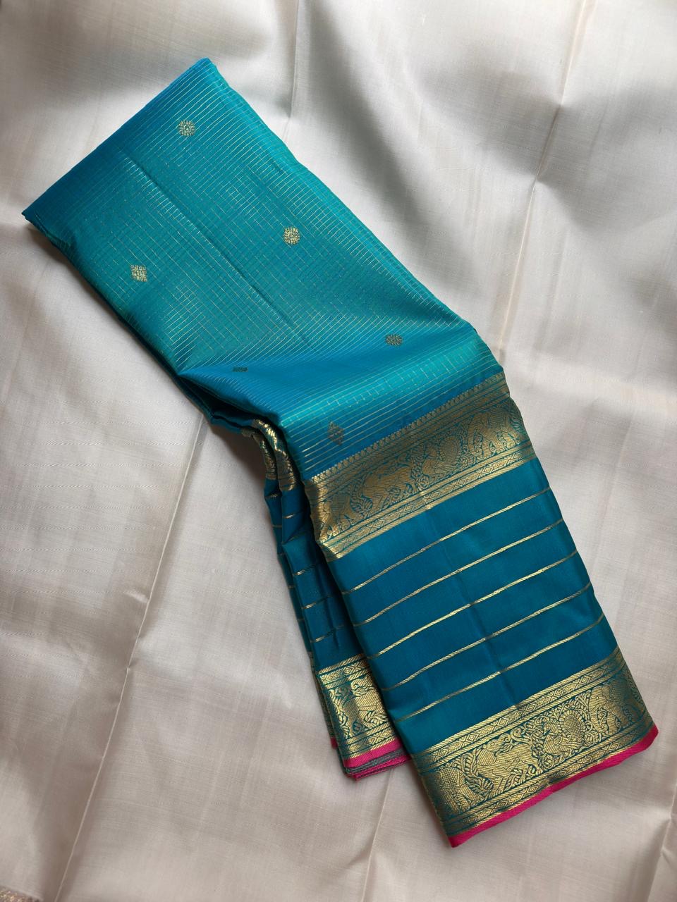 Teal-blue Pure Silk Kanjipuram Zari Kattam saree with fine gold grid and a stylised bird-motif border.
