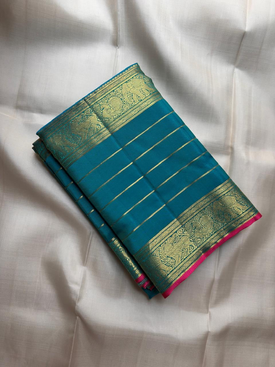 Teal Kanchipuram silk body with fine classic-gold zari lines forming a close ordered grid.