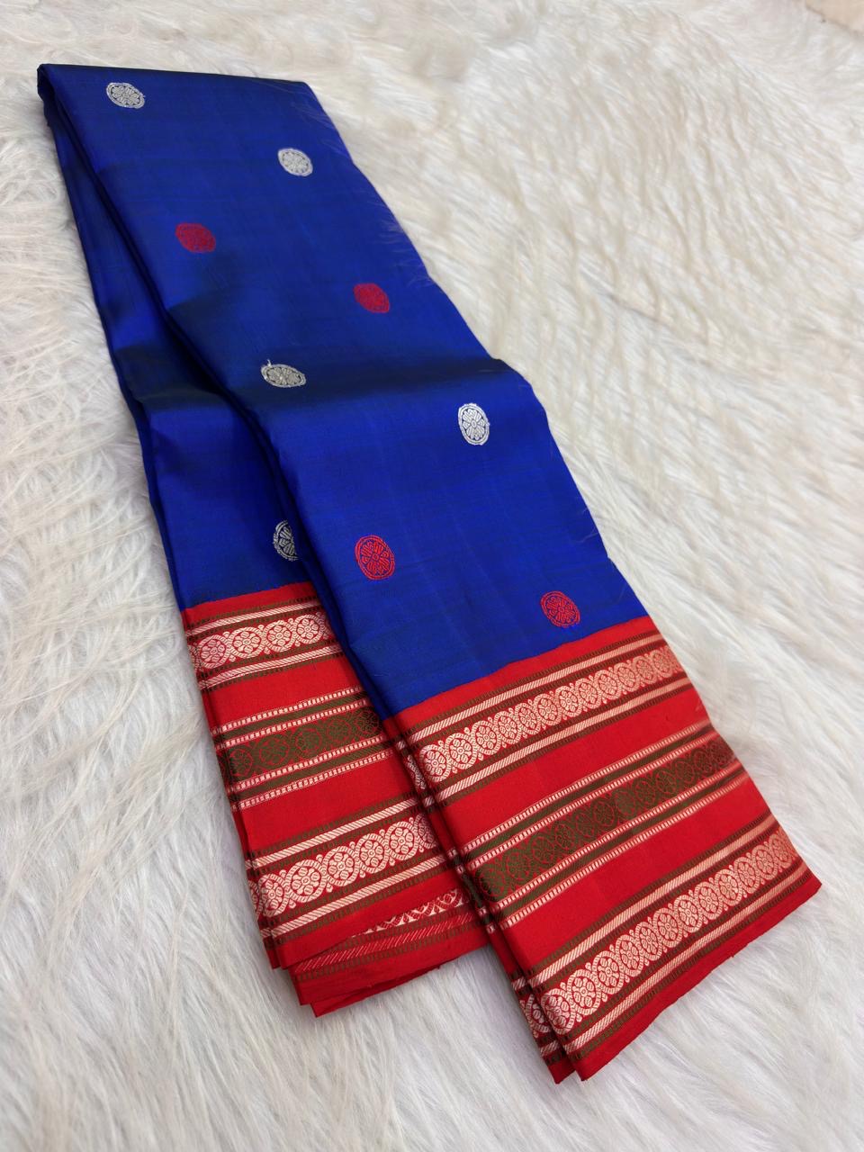 Neelam blue handwoven Pattupet Kanchipuram saree displayed open with contrasting red floral border and pallu