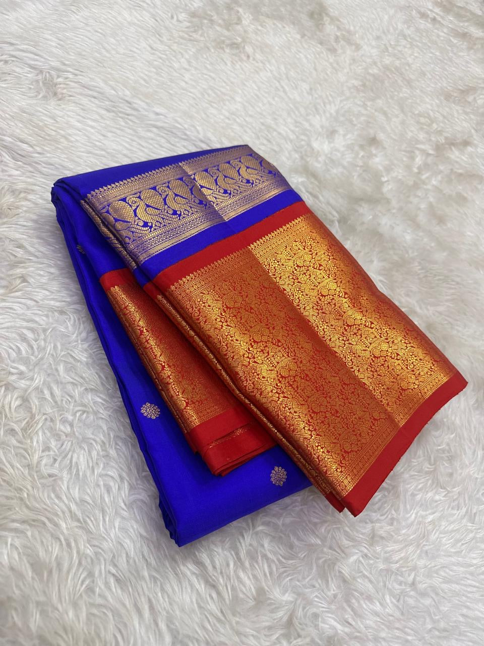 Royal blue Kanchipuram silk body with individually spaced classic-gold zari buttas across an open silk field.