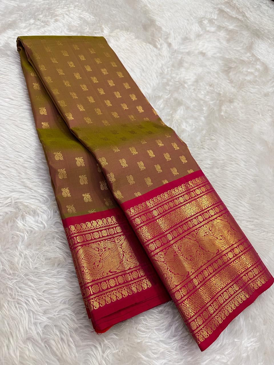 Traditional small peacock buttas woven across the muted olive and brown silk body.