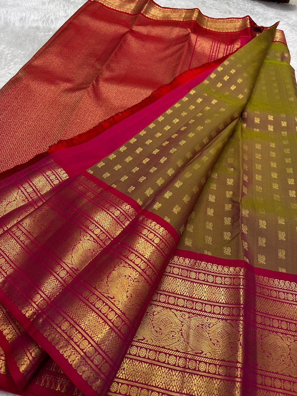Contrast between olive-bronze body, ruby-red pallu and richly framed gold zari border.