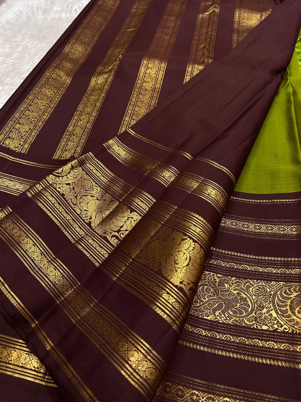 Gold mayil peacock buttas repeated between the other figured motifs on the green silk.