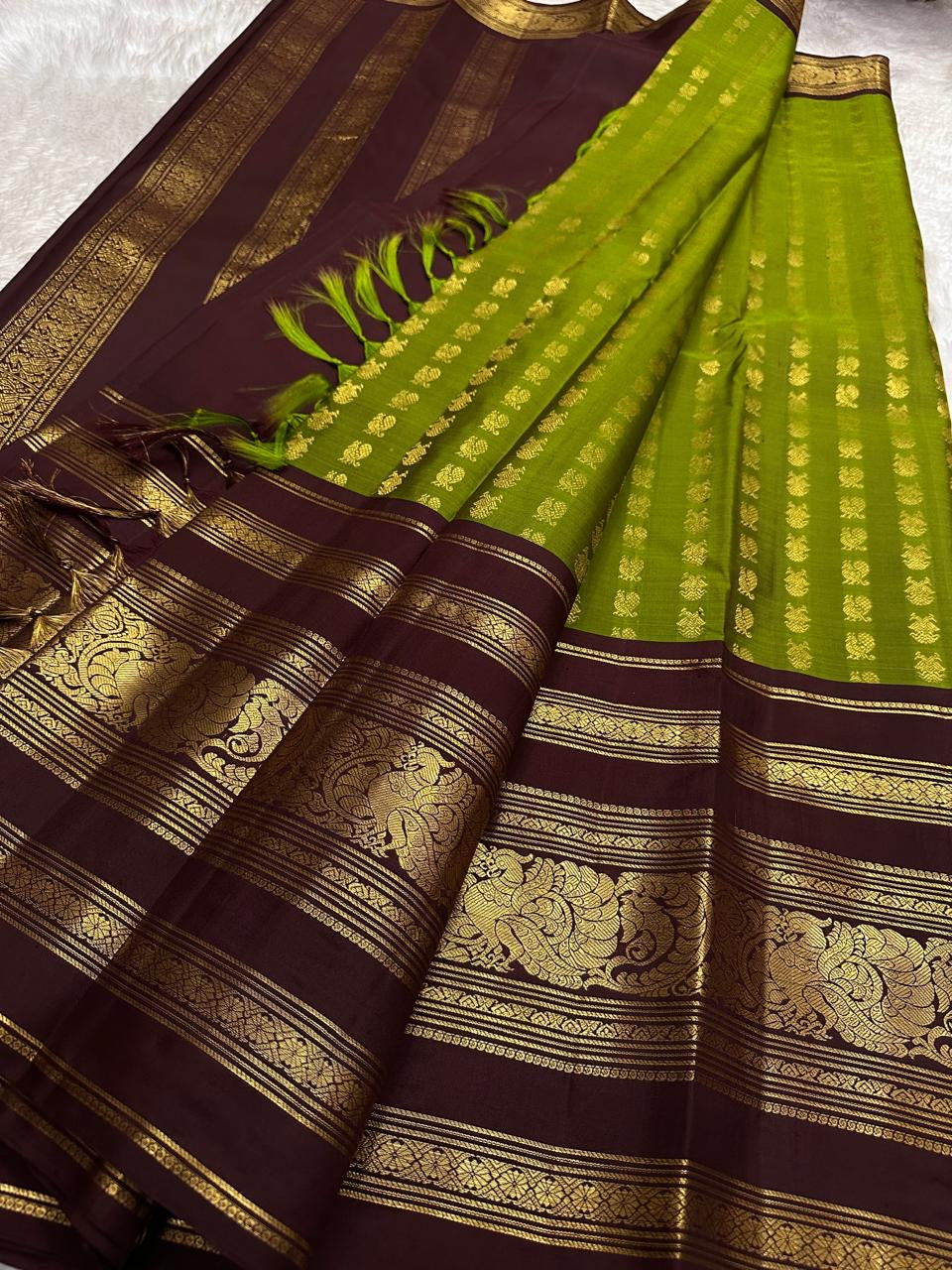 Broad deep plum-brown border showing a repeated array of peacocks in warm gold zari.
