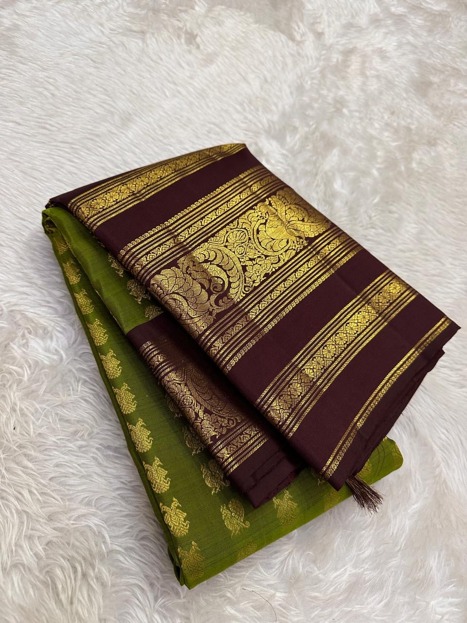 Handwoven olive-green Kanjivaram silk with contrasting plum-brown border and gold zari detail.