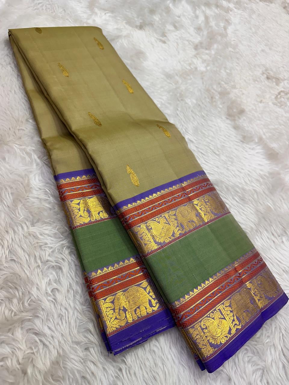 Sage olive Kanjivaram Rettapet saree — antique-gold zari elephant border motif close-up