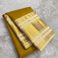Earthy yellow-gold Kanchipuram silk with an olive undertone and small restrained classic-gold zari buttas.