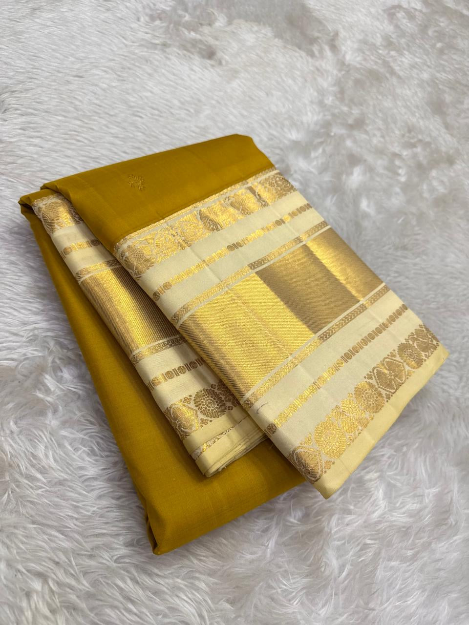 Earthy yellow-gold Kanchipuram silk with an olive undertone and small restrained classic-gold zari buttas.