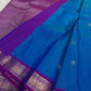Pure Kanchipuram silk saree spread open with a teal blue body, zari buttas, and a contrasting purple pallu section.