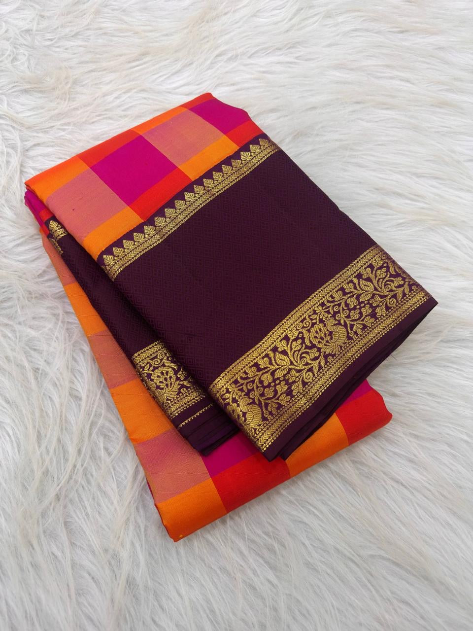 Aubergine peacock and Kodi Malar zari border on an orange and Rani pink Kanchipuram saree.