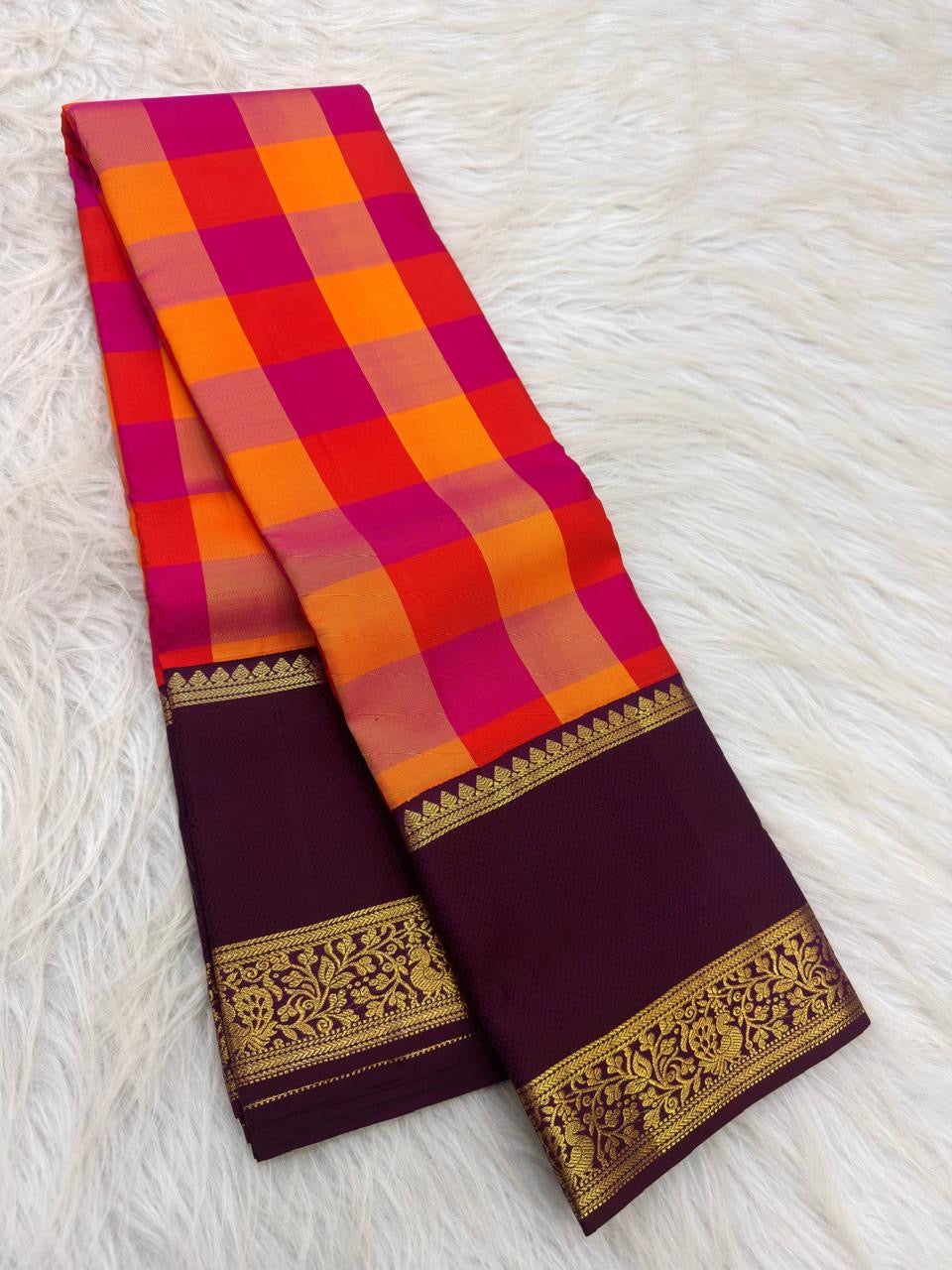 Vivid orange and Rani pink checks of a Paalum Pazhamum Kanchipuram saree.