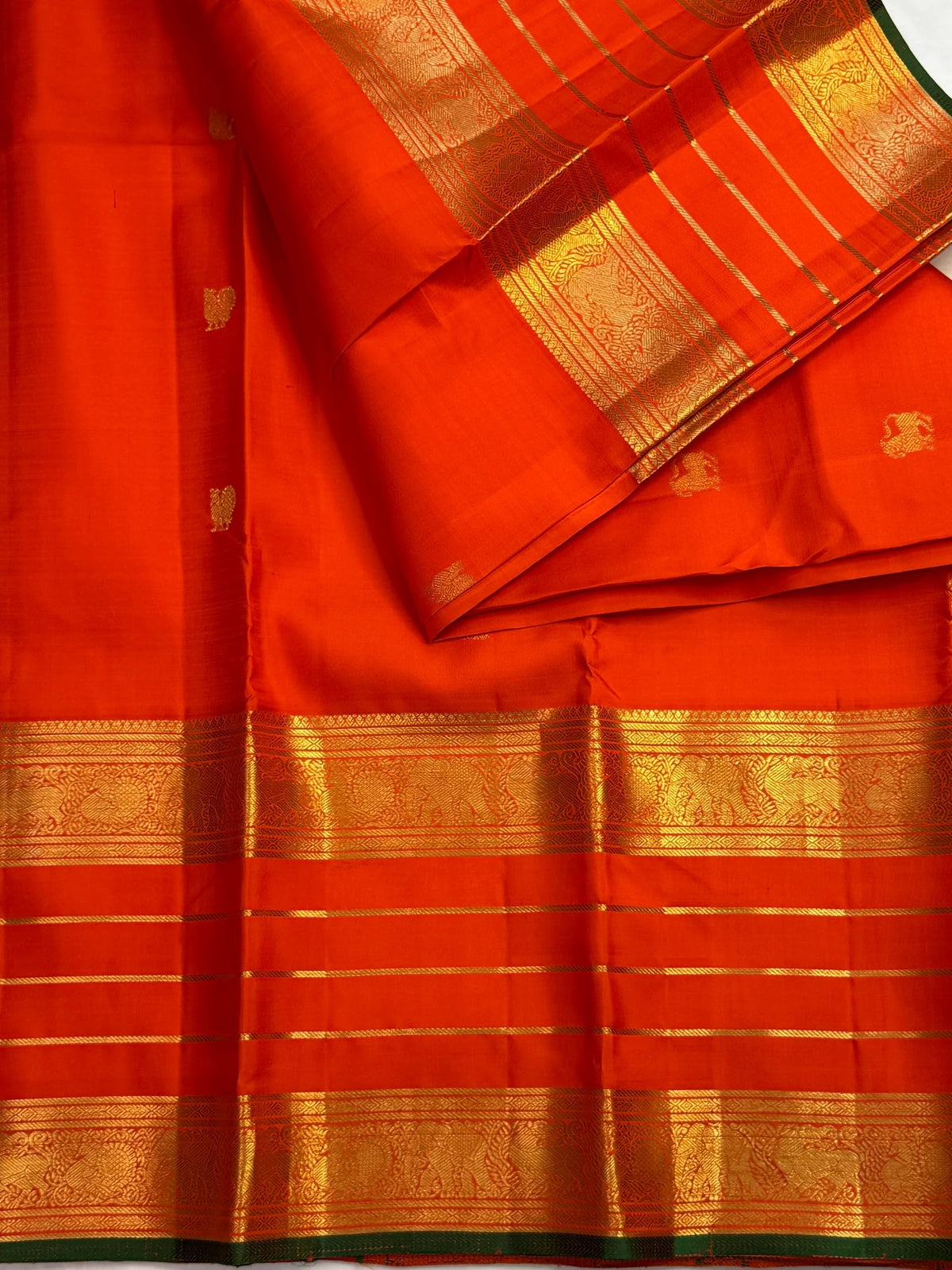 Varisaipet border of handwoven zari and thin zari bands on a radiant jewel-toned orange Kanchipuram silk saree.