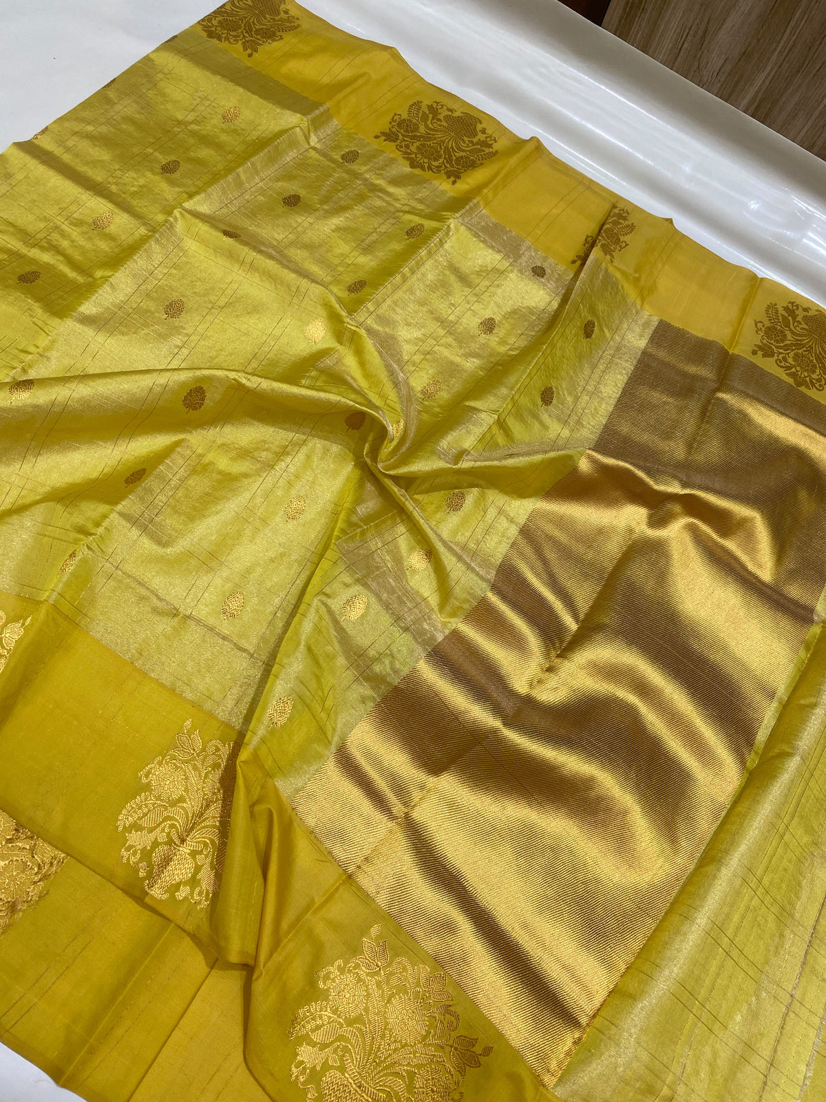 Close view of Turmeric Gold Chanderi saree showing petite gold buttas, fine checks and large floral foliage border motif