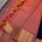 Folded pure Kanchipuram silk saree in purple black tones showing silk texture and shimmering zari border detail.