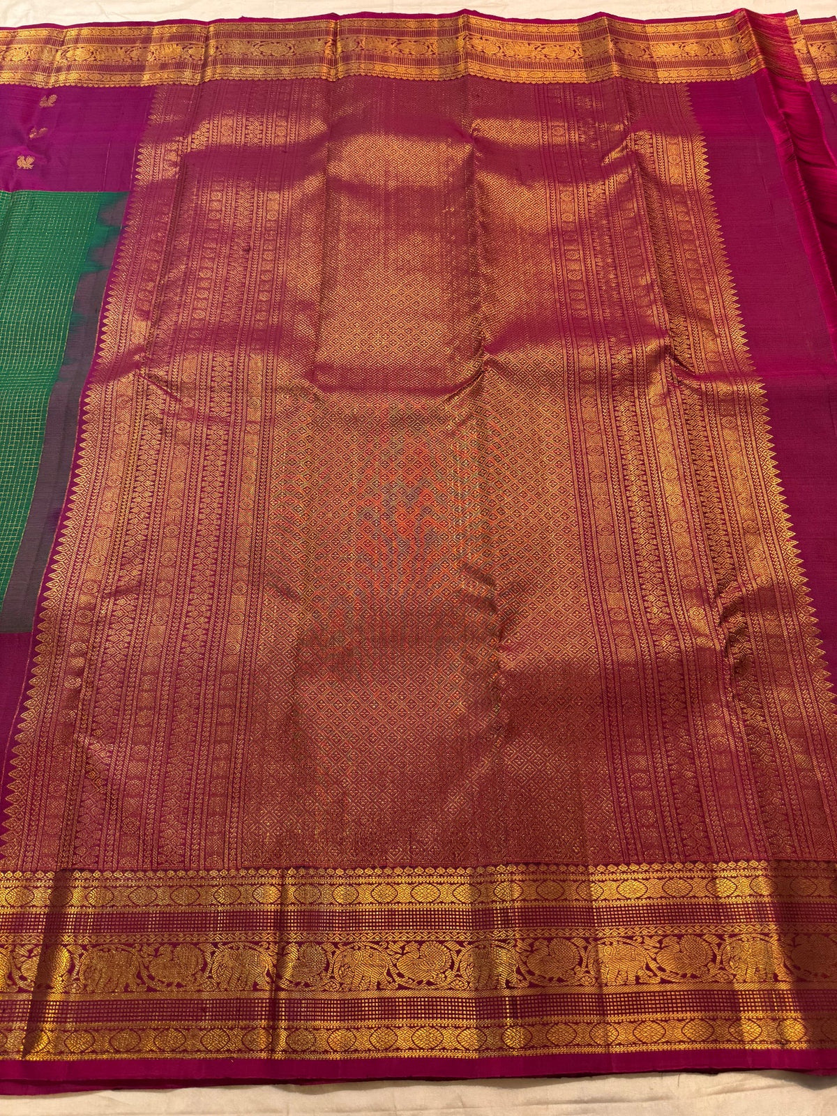 Close view of warm-gold ornamental zari registers on saturated Rani Pink Kanchipuram border.