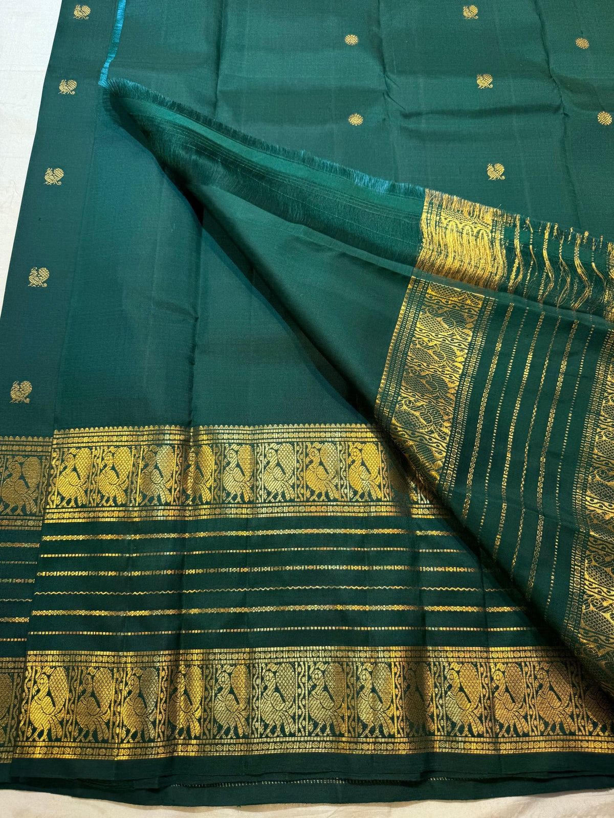 Close view of luminous gold zari buttas across Deep Pachai Green pure mulberry silk.