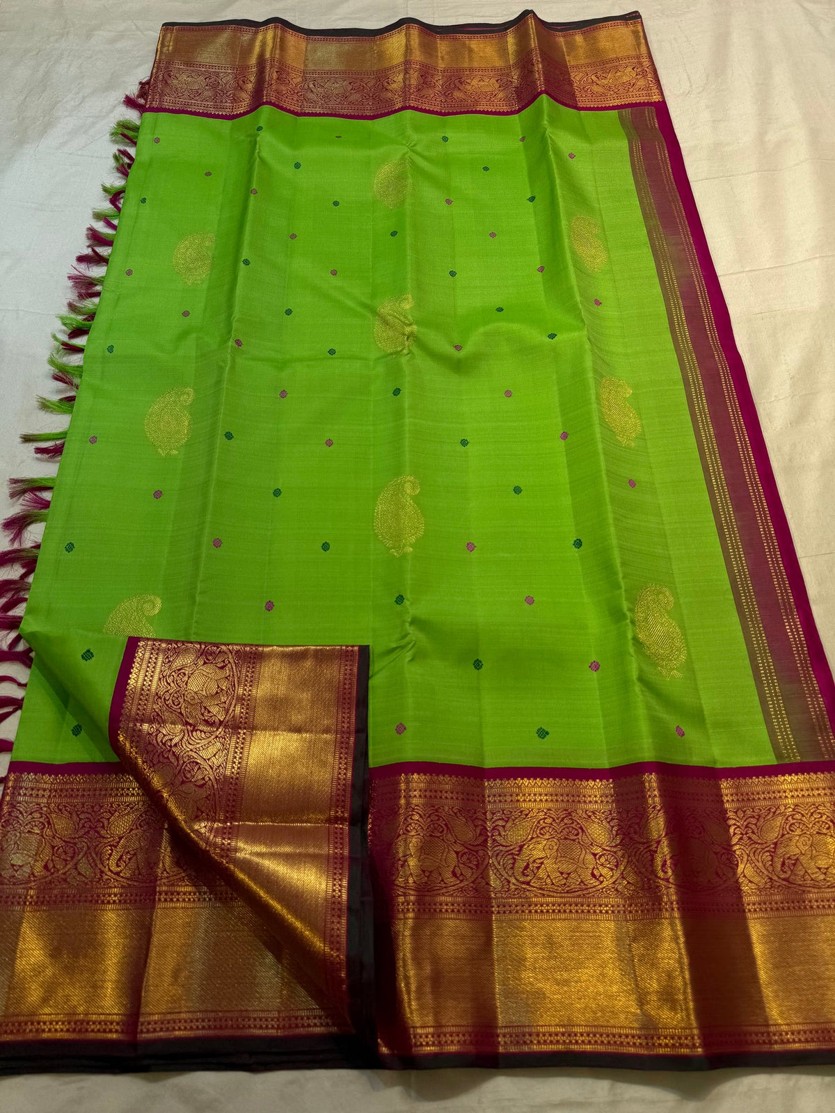 Bright green handwoven Kanchipuram Korvai saree with tiny pink and green silk-thread buttas.