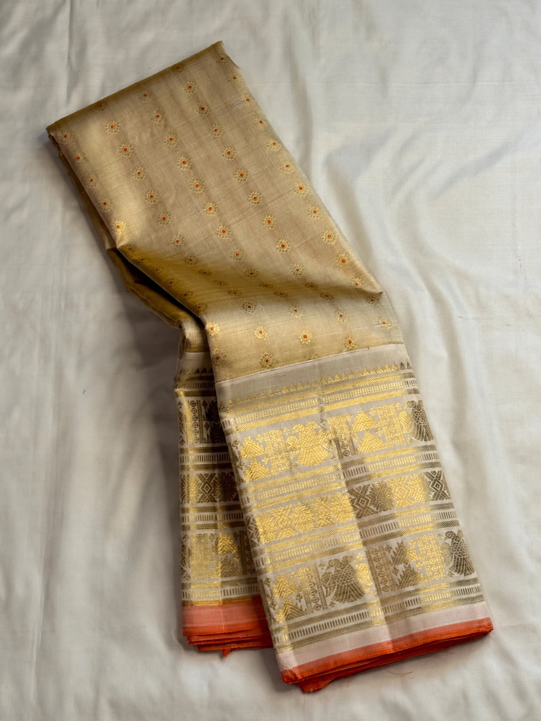 Pale gold handwoven Pure Silk Kanjeevaram Butta saree with orange Meenakari Kamalam motifs and coral-orange selvedge, border detail