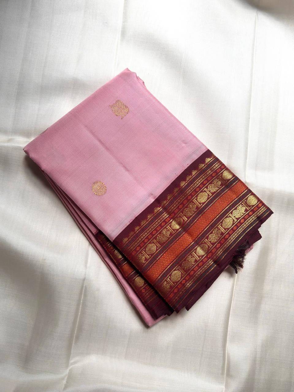 Pale Blush Pink handwoven Kanchipuram Korvai saree with gold ornamental buttas and deep Aubergine zari border.