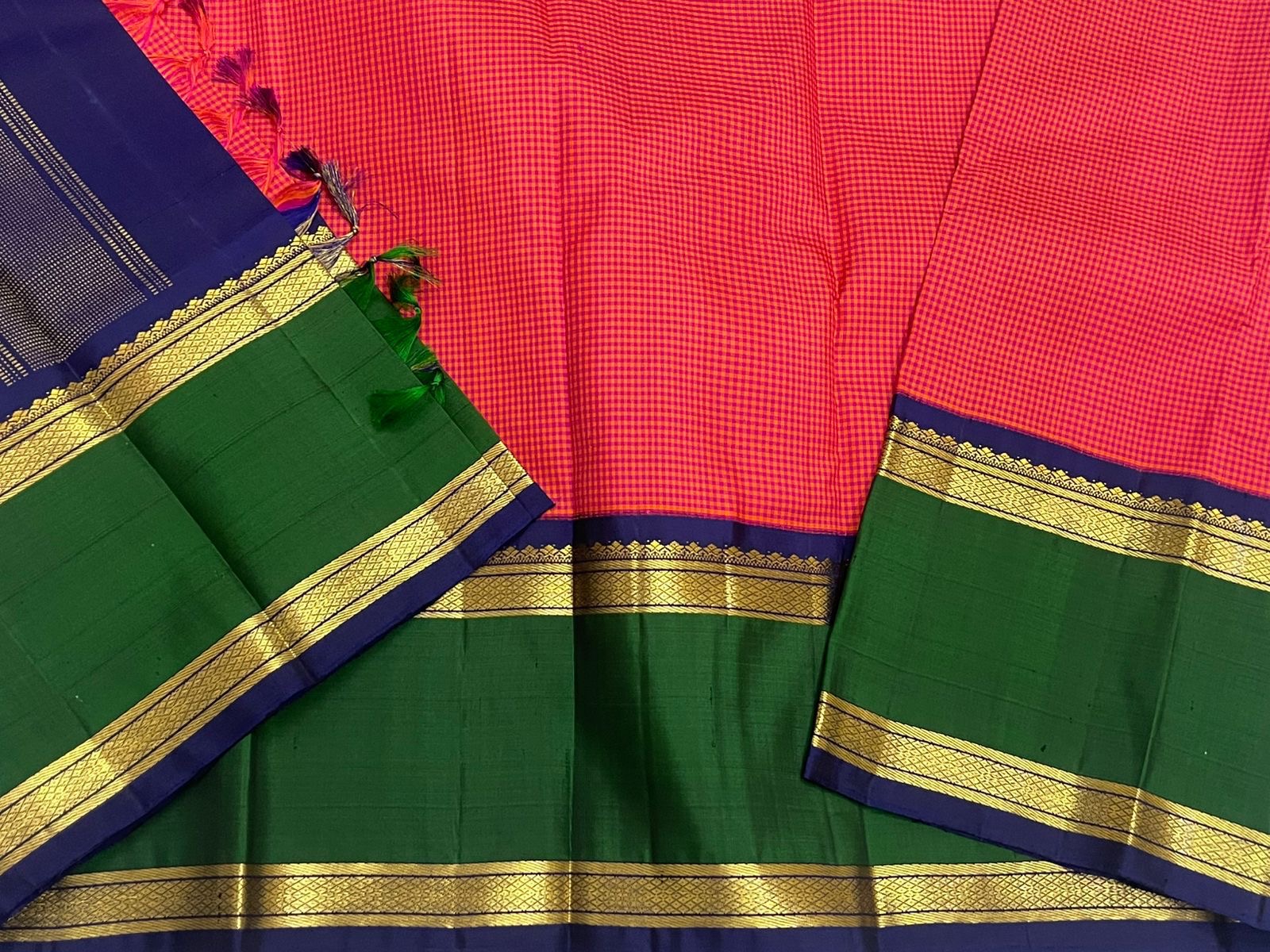 Full flat lay of pure Kanchipuram silk saree with red checked body, green border, navy pallu with vertical zari stripes, and gold zari bands.