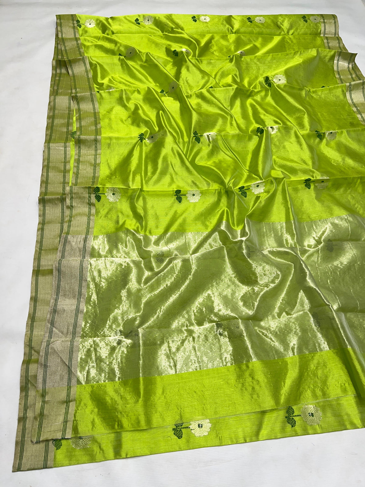 Parrot green handloom Chanderi saree with white flower motifs and softly radiant metallic detailing.