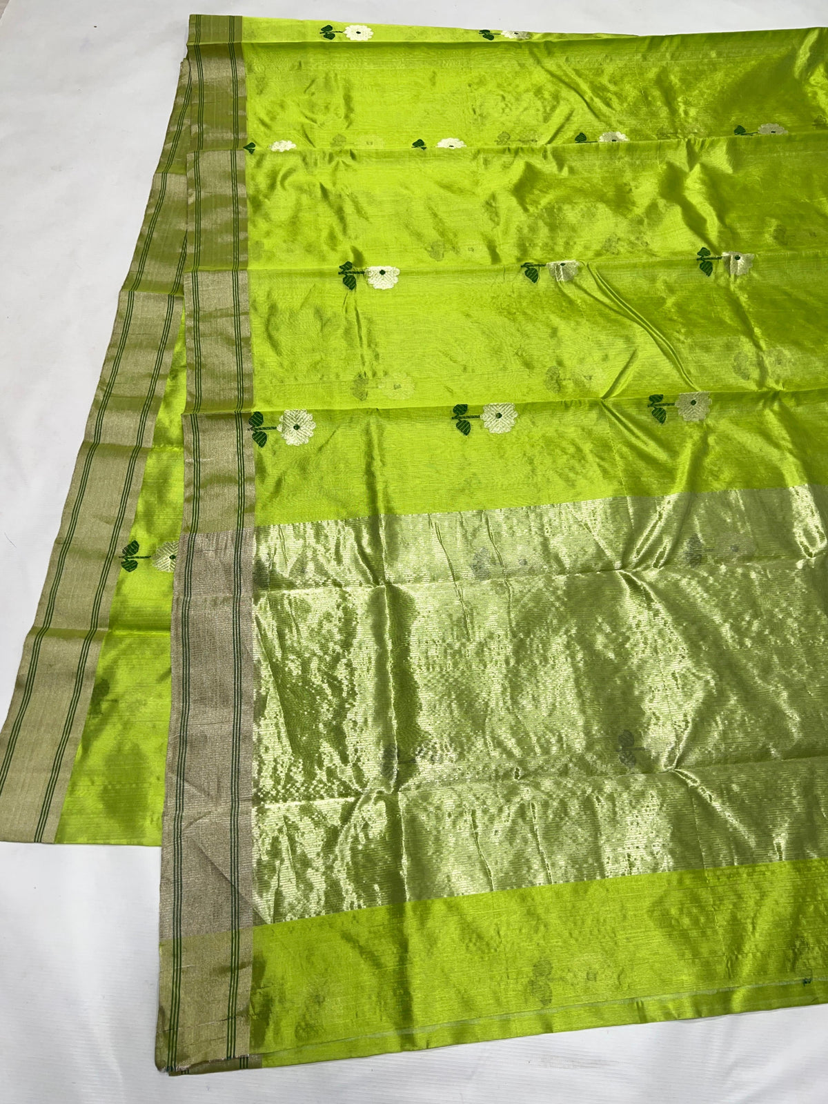 Soft champagne-silver metallic pallu on a parrot green Chanderi handloom saree.