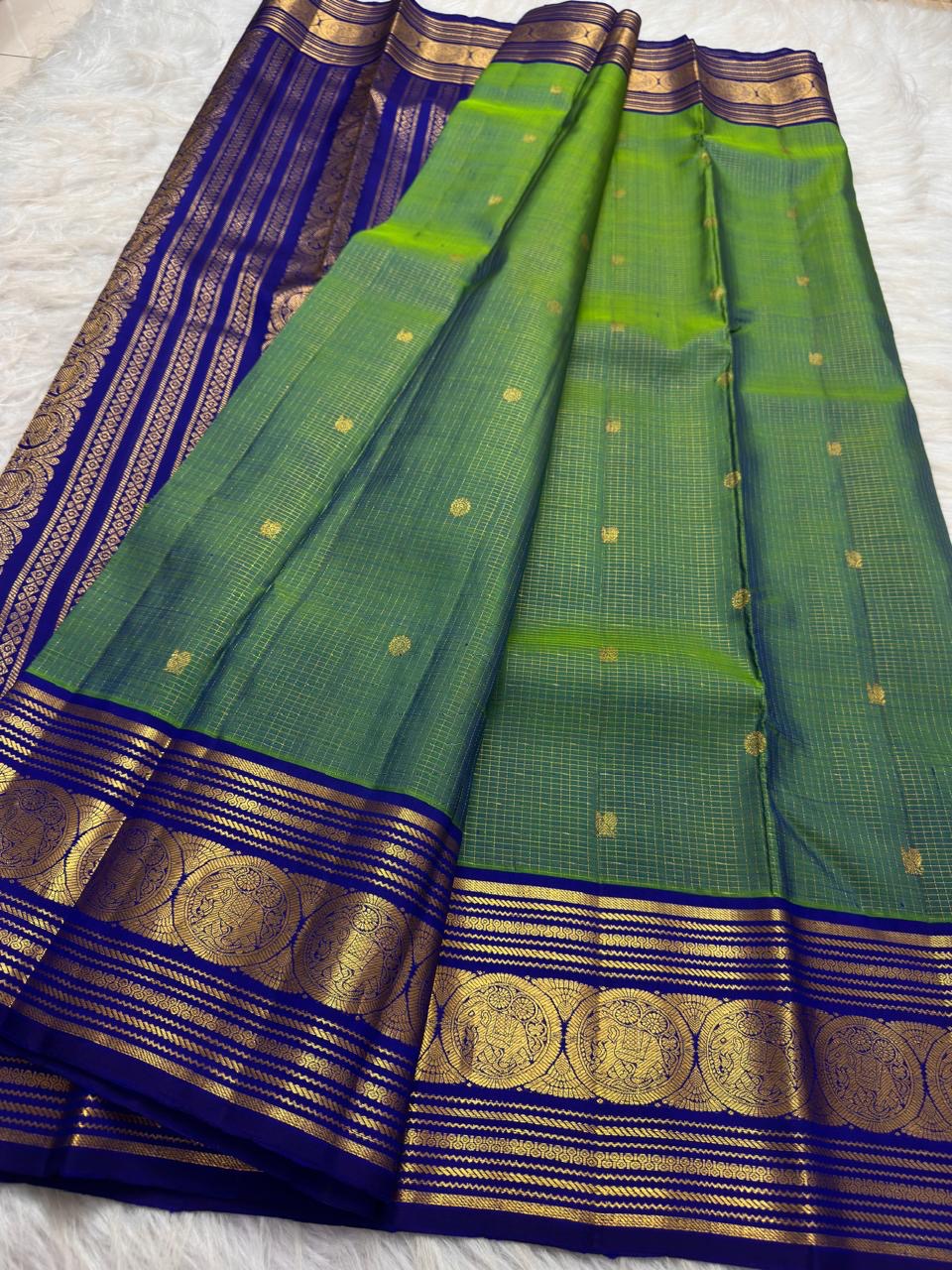 Fine gold Zari Kattam checks and buttas across the parrot green silk body