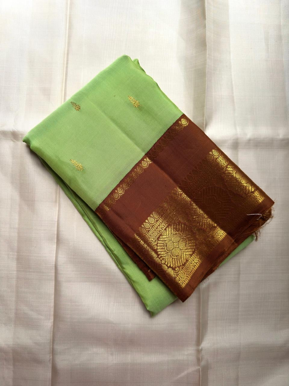 Parrot Green Kanjivaram silk saree with Deep Kaapi Brown contrast border and gold Poo Buttas