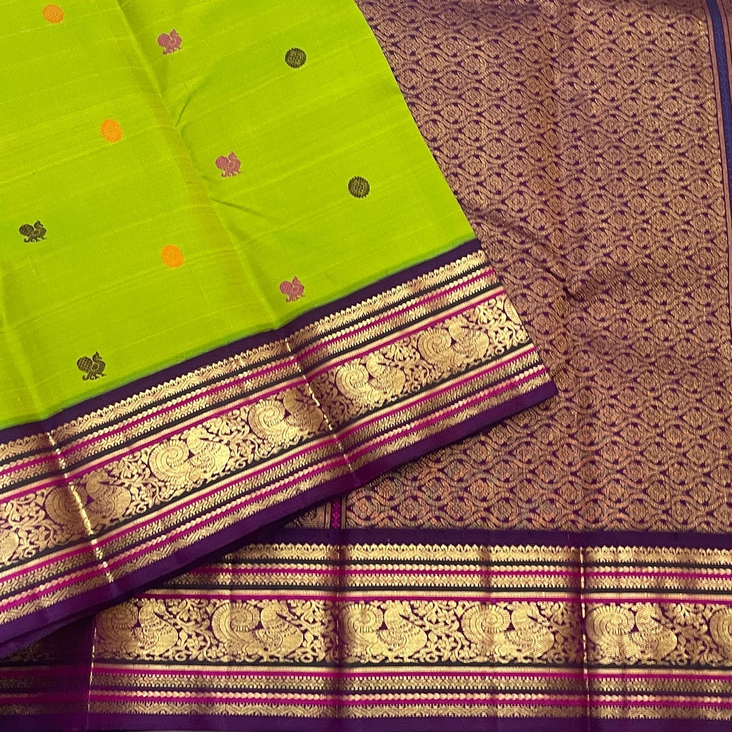 Folded Parrot Green Pure Silk Kanchipuram Korvai saree with multicoloured silk-thread buttas and Deep Purple Mayil zari border.