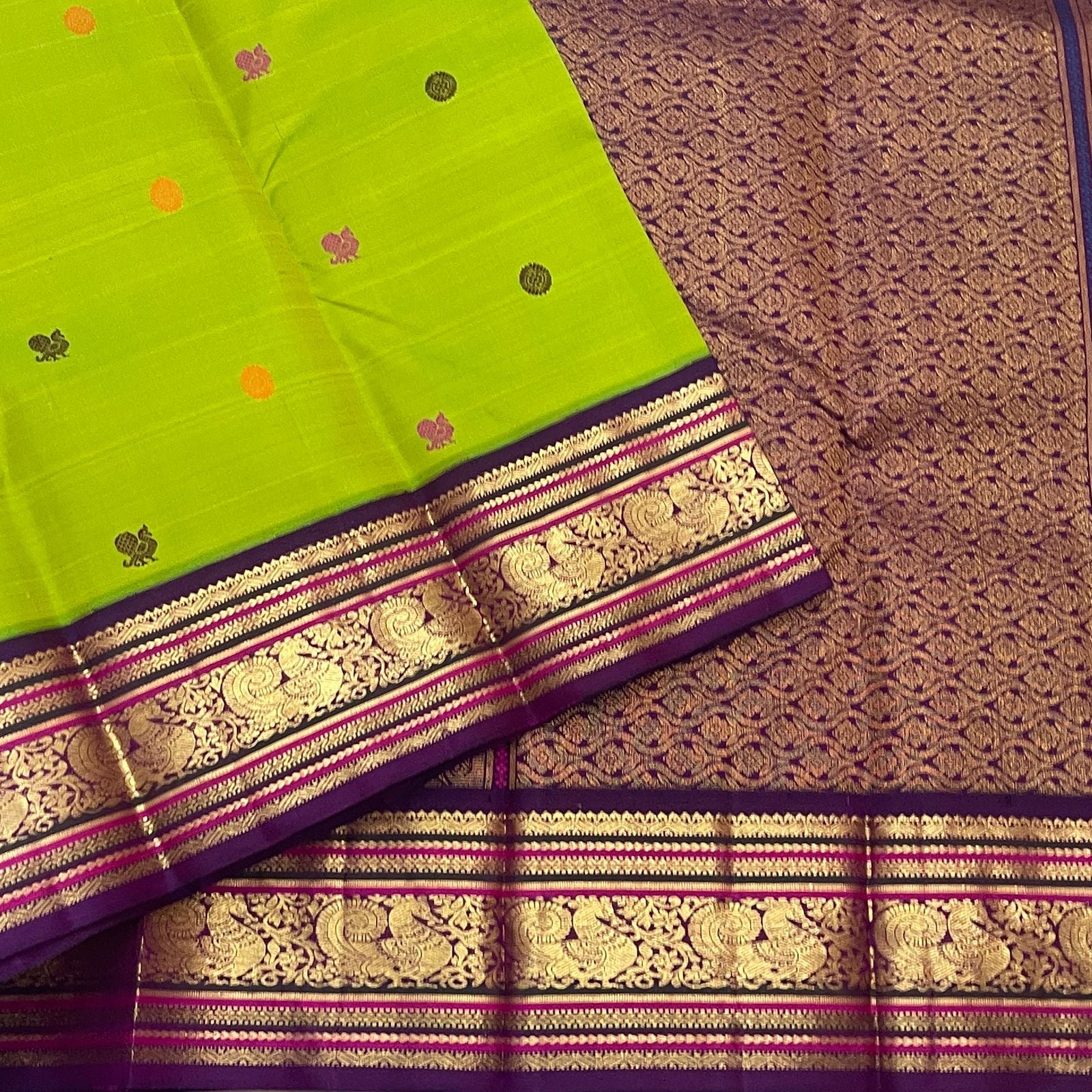 Folded Parrot Green Pure Silk Kanchipuram Korvai saree with multicoloured silk-thread buttas and Deep Purple Mayil zari border.