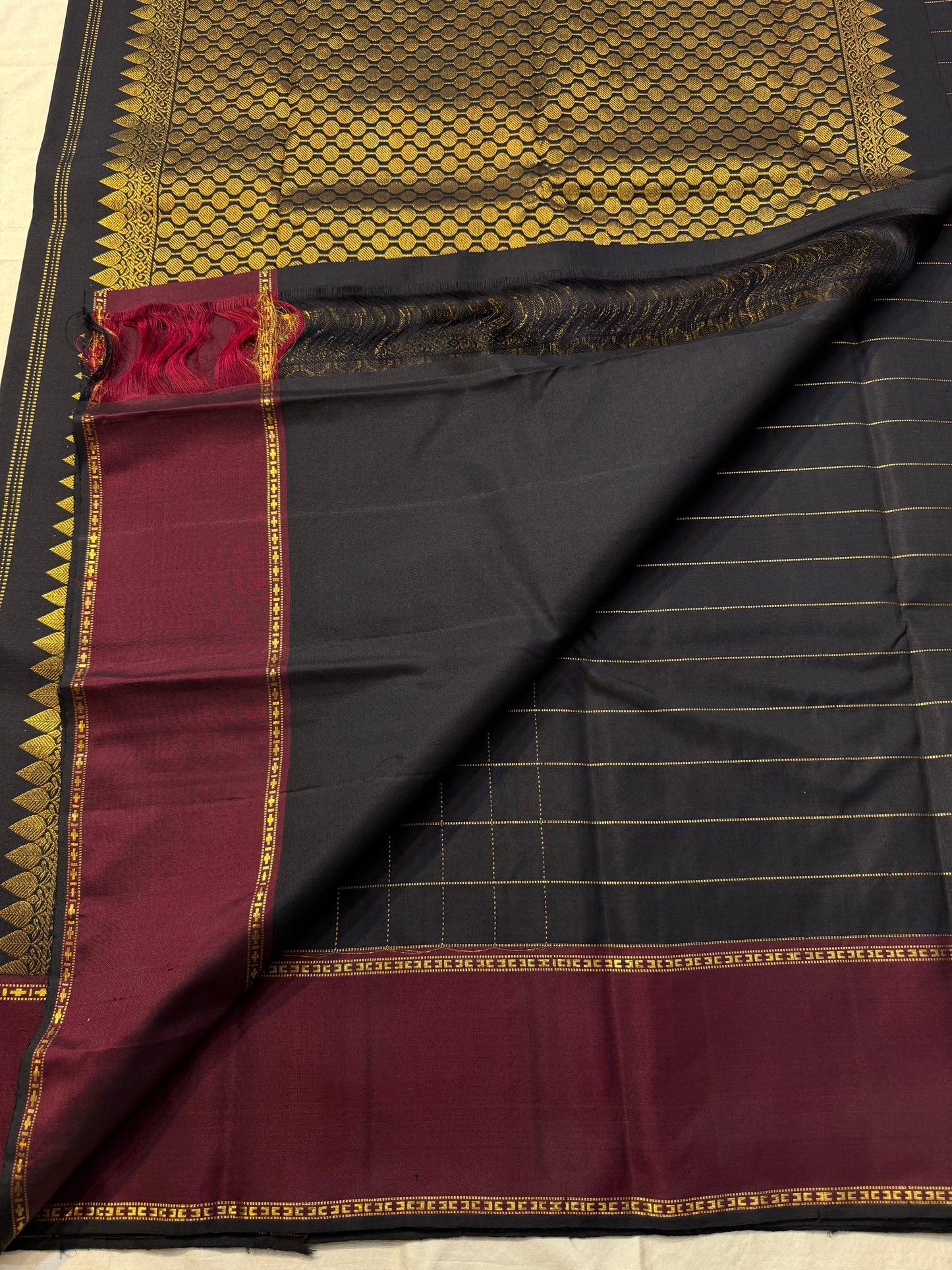 Flat-lay of Pure Kanchipuram Silk Saree highlighting the checked black body with maroon zari border panel and border band