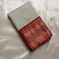 Folded sage green Pure Kanchipuram silk saree with maroon zari woven border and gold paisley motif