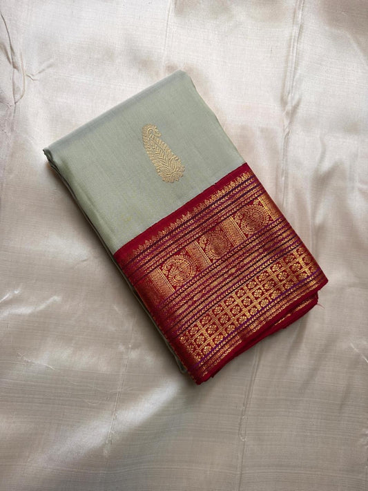 Folded sage green Pure Kanchipuram silk saree with maroon zari woven border and gold paisley motif