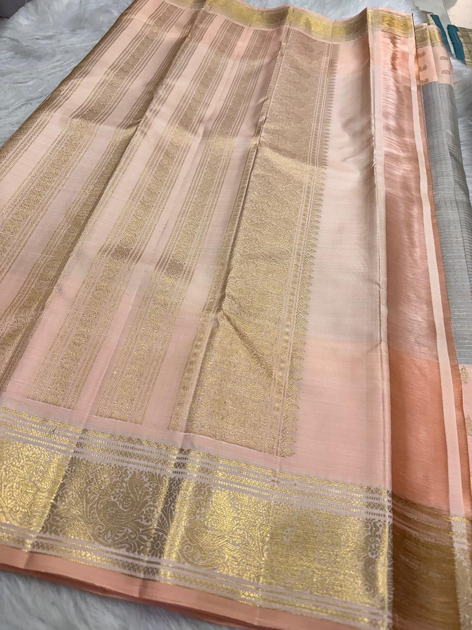 Handwoven peach pink and grey Kanjivaram saree with broad antique-gold paisley border.